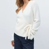 White sweater with tied sleeves worn by a person on a light gray background